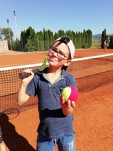 Ученик Tennis Prosto с мячом на грунтовом корте на сборах